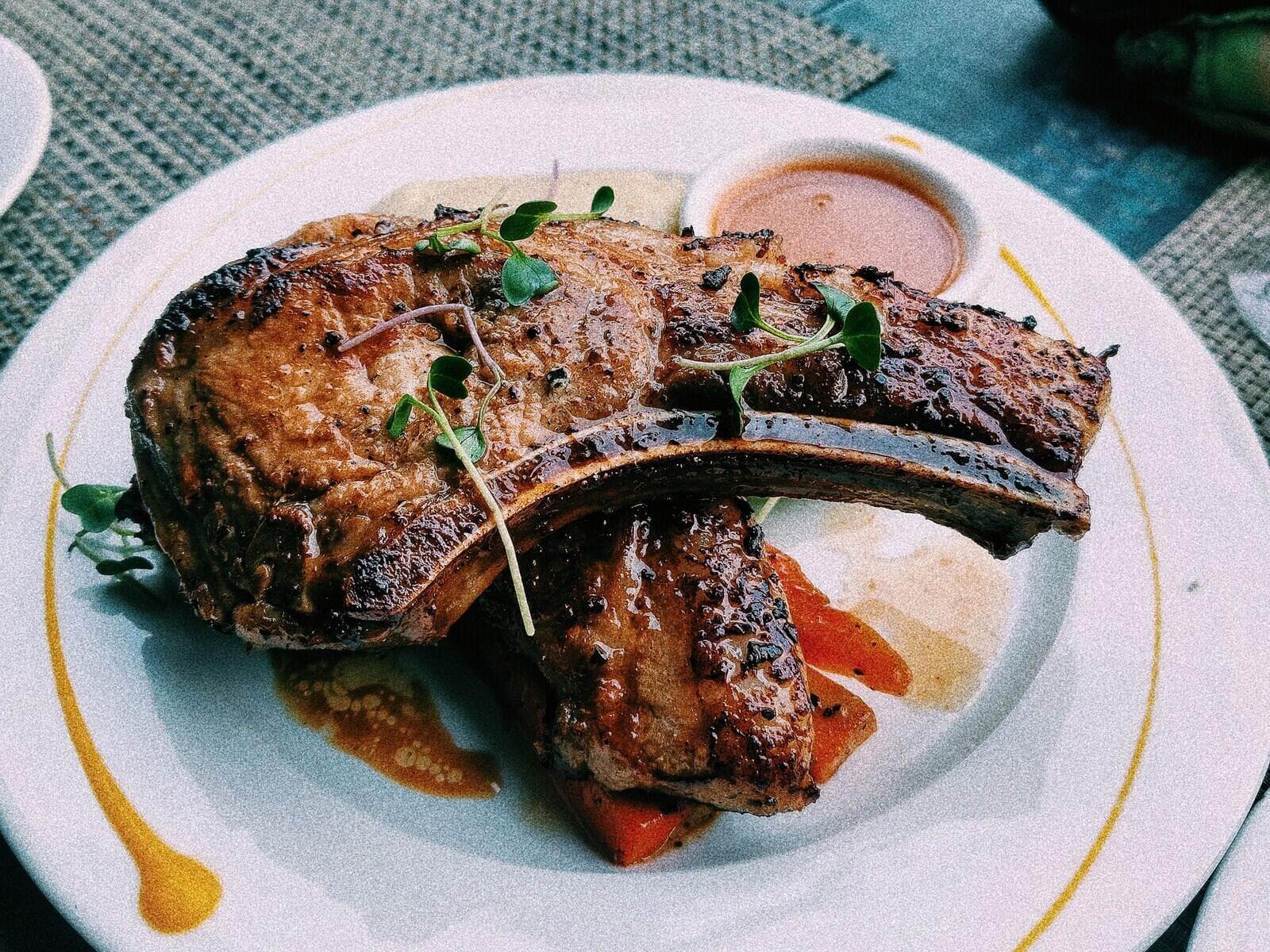 Bone-in glazed pork chop on a white plate with fresh herbs.